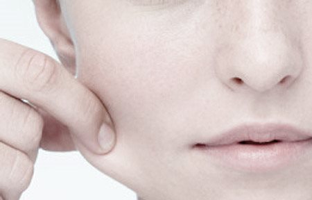 Jeune femme tirant sur sa joue droite.
