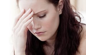 Femme en position pensive, avec une main sur le front.