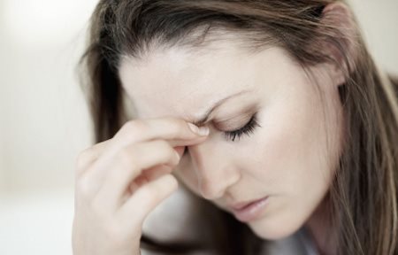 Femme au regard baissé, air stressé - sa main touche son front