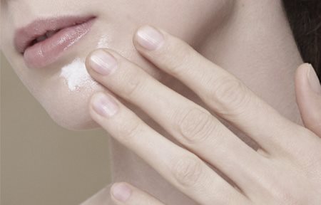 Femme qui s'applique de la crème sur le menton.