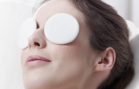 Femme qui se détend avec des compresses sur les deux yeux.
