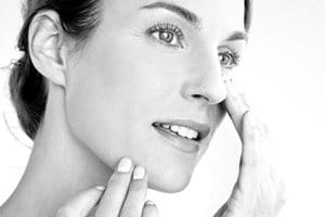 Femme appliquant la crème sur sa joue.