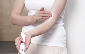 Femme appliquant la crème calmante intensive Eucerin AtopiControl dans le pli du coude.