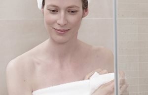 Femme après la douche, enroulée dans une serviette, une serviette en turban sur la tête.