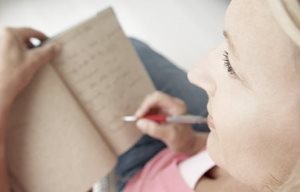 Femme écrivant quelque chose sur un bloc-notes