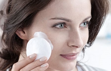 Femme se nettoyant le visage avec un coton